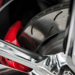 Close-up of a shiny car wheel rim showing a red brake caliper and ventilated disc, both previously benefiting from Teflon™ High Temp Grease [DISCONTINUED] for smooth, efficient performance.