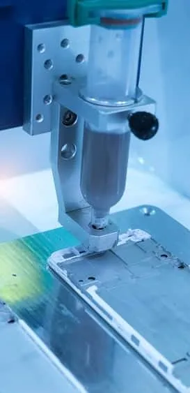 Close-up of precision manufacturing equipment with a syringe-like component used in industrial processes for electronics assembly.